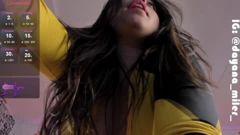 Media: Video of a young woman with long, dark hair, wearing a yellow and black shirt, in a dimly lit room with a digital display showing temperature and humidity.