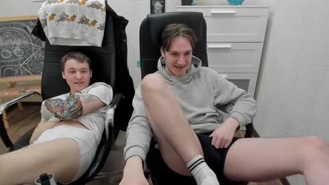 Media: Video of two young men in a room; one lying in a chair, the other sitting, both wearing casual clothes, legs crossed, laughing.