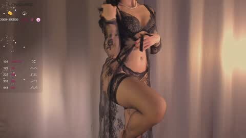 Media: Video of a curvaceous woman in black lace lingerie, posing provocatively in a dimly lit room with vertical blinds. Her skin is light, and she has a slim waist and ample breasts.