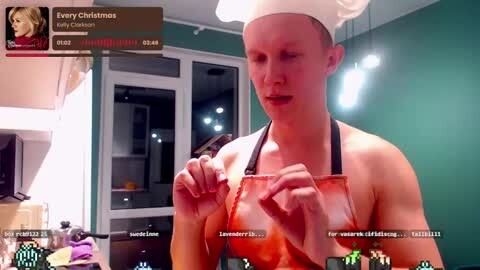 Media: A video shows a muscular, shirtless man in a white chef's hat and apron, holding a red-colored liquid, in a modern kitchen with teal walls.