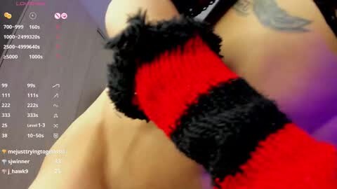 Media: Video of a close-up of a person's arm wearing a red and black striped arm band with black fur trim, showcasing a tattoo on the shoulder.