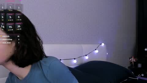 Media: A video shows a woman with short dark hair lying on a bed with a blue blanket, wearing a teal shirt. A digital overlay displays a weather forecast and social media notifications.