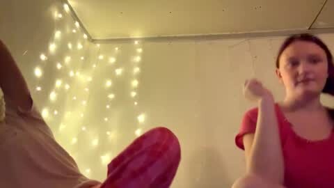 Media: Video of a woman in a red shirt, smiling, and a large erect penis, against a background of fairy lights.