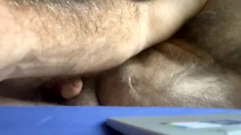 Media: Video of a close-up, blurry human torso with visible pubic hair, lying on a blue surface, possibly a bed or couch, with a white object (likely a phone) partially visible in the bottom right corner.