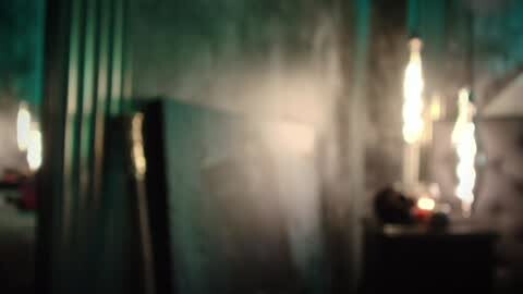 Media: A dimly lit video featuring a misty, abstract scene with blurred, glowing lights and indistinct shapes, possibly in a room with a vintage, mysterious atmosphere.