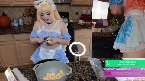 Media: Video of a blonde woman in a blue and white maid outfit, preparing food in a kitchen with beige cabinets and a granite countertop.