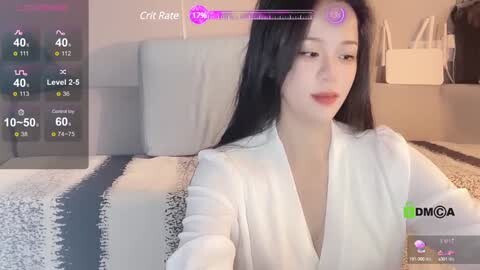 Media: Video of a young Asian woman with long black hair, fair skin, and red lipstick, wearing a white blouse, sitting on a bed with a black-and-white striped blanket. A \"DMCA\" watermark appears at the bottom right.