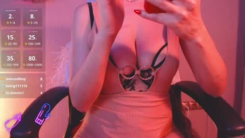 Media: Video of a woman with light skin, large breasts, wearing a revealing black and white lace bodysuit, sitting on a black office chair, holding a red phone. Background shows a digital clock and a purple vibrator.