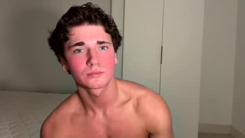 Media: Video of a young, shirtless white man with curly brown hair and blue eyes, standing indoors against a plain white background.