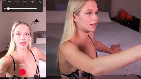 Media: Video of a blonde, fair-skinned woman with a slim build, wearing a black lace bra, sitting on a bed in a modern bedroom. The background includes a nightstand with pumpkins.