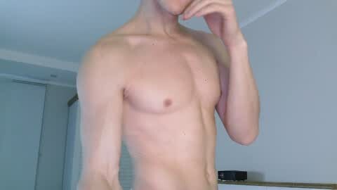 Media: Video of a shirtless, slender, fair-skinned man with a small chest and defined abs, standing in a minimalist, brightly lit room with white walls and blinds.