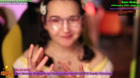Media: A video of a woman with fair skin and glasses, wearing a yellow dress, clapping in a blurry background. Text overlays mention her Twitch channel and Christmas activities.