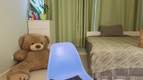 Media: Video of a cozy, modern bedroom with a beige teddy bear on a white dresser, a blue slide, and a bed with a striped comforter.