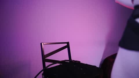 Media: A video of a black metal chair with a white tablecloth draped over it, set against a vivid purple wall, creating a striking color contrast.
