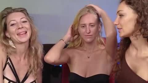 Media: Video of three women with different hair styles and attire, laughing and playfully touching each other's hair, seated indoors.