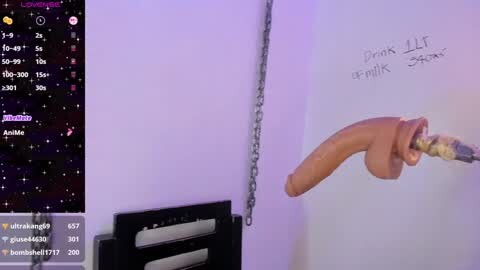 Video of a white wall with a large, realistic drawing of a penis and testicles, held by a chain. The wall also features a digital clock and a video game controller.