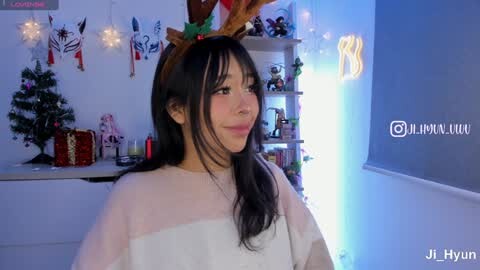 Media: A video of a young Asian woman in a white bathrobe, wearing a festive deer headband, in a cozy, Christmas-decorated room with a small tree, presents, and lit string lights.