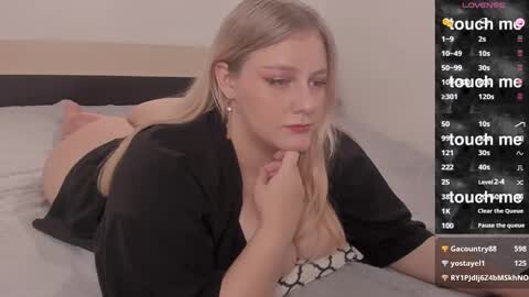 Media: A video of a blonde woman lying on a bed, wearing a black robe, with a touch-me interface overlay.