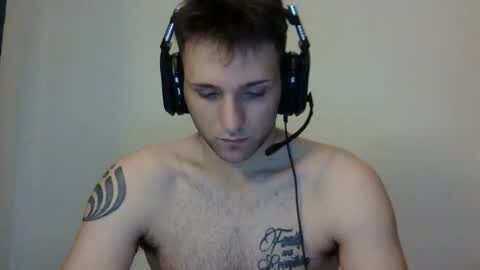 Media: A video of a shirtless man with light skin, short dark hair, wearing large black headphones and a microphone, displaying tattoos on his shoulders.