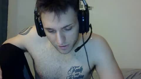 Media: Video of a shirtless man with fair skin, short dark hair, wearing black headphones, with a visible tattoo on his chest. He has a focused expression, possibly gaming.
