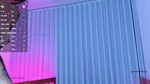 Media: A video of a room with a large, vertical blue curtain and purple lighting. The left side shows a digital clock and a person's face, likely taken from a video game.