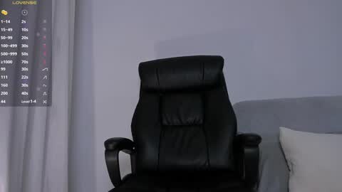 Media: Video of a modern black leather office chair with a high backrest in a minimalist, gray-walled room. A digital clock displaying \"9:09\" is visible on the left.