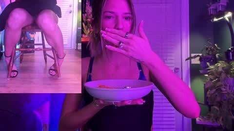 Media: A video featuring a woman with light skin, shoulder-length blonde hair, wearing a black top, eating from a white bowl, with a purple-lit room in the background.