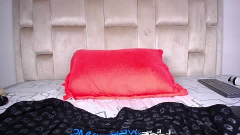 Media: A video of a bed with a beige, tufted headboard, a bright pink pillow, and a black and white patterned duvet.