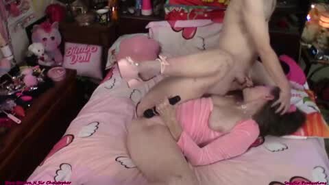 Media: Video of two nude women in a pink-themed bedroom, one kneeling on a bed, the other straddling her, engaging in sexual activity.