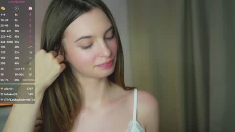 Media: Video of a young Caucasian woman with long, straight brown hair, wearing a white lace bralette, standing in a softly lit room, with a calendar displaying \"u/lelelelele\" and \"u/whosays\" on the left.