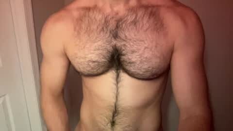 Media: Video of a naked man with a hairy chest, pale skin, and visible muscles. He stands indoors, with a white door in the background.