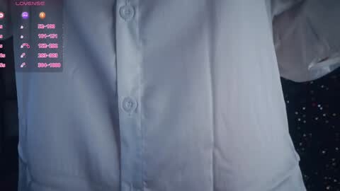 Media: A video of a white, button-down shirt with visible buttons, positioned against a dark background, displaying a digital screen with pink icons and text on the left.