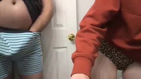 Media: Video of a person in a red sweatshirt, leopard print underwear, pulling down blue striped pajama pants, revealing a flat stomach, in front of a white door with a gold doorknob.