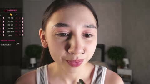 Media: Video of an Asian woman with fair skin, dark hair, and a nose ring, wearing a grey tank top, indoors with a calendar screen overlay.