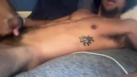 Media: Video of a muscular, naked man with a tattoo of Japanese kanji on his left ribcage, lying on a grey bed. His head is slightly out of frame.